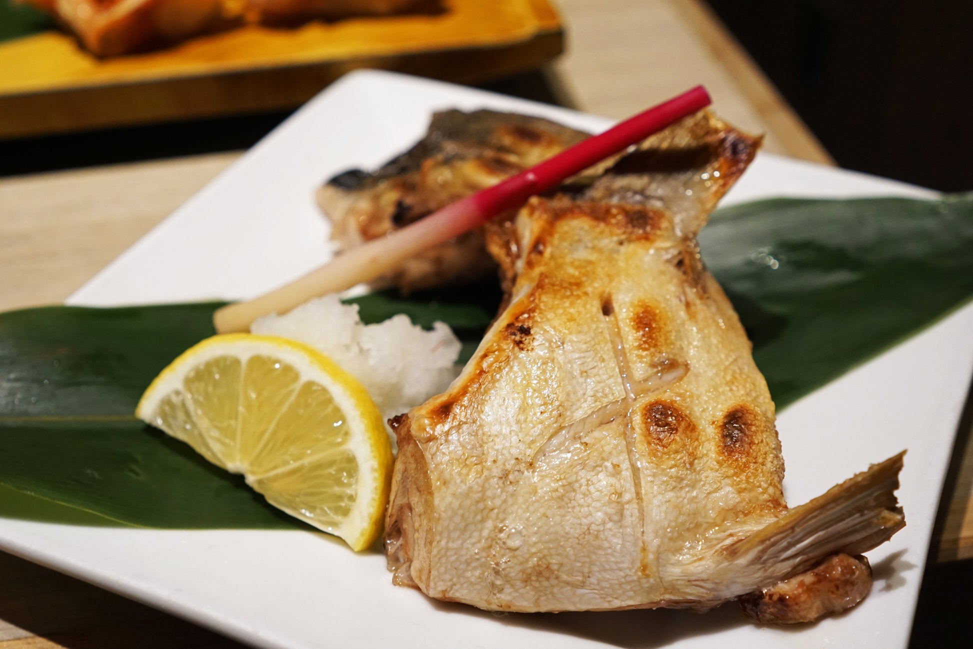 Grilled fish on a plate with lemon and chopsticks intershell fish